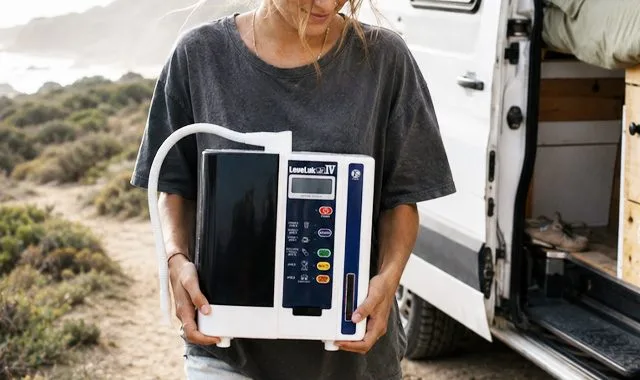 Un viaggiatore che tiene il compatto LeveLuk JR IV accanto a un camper sulla costa